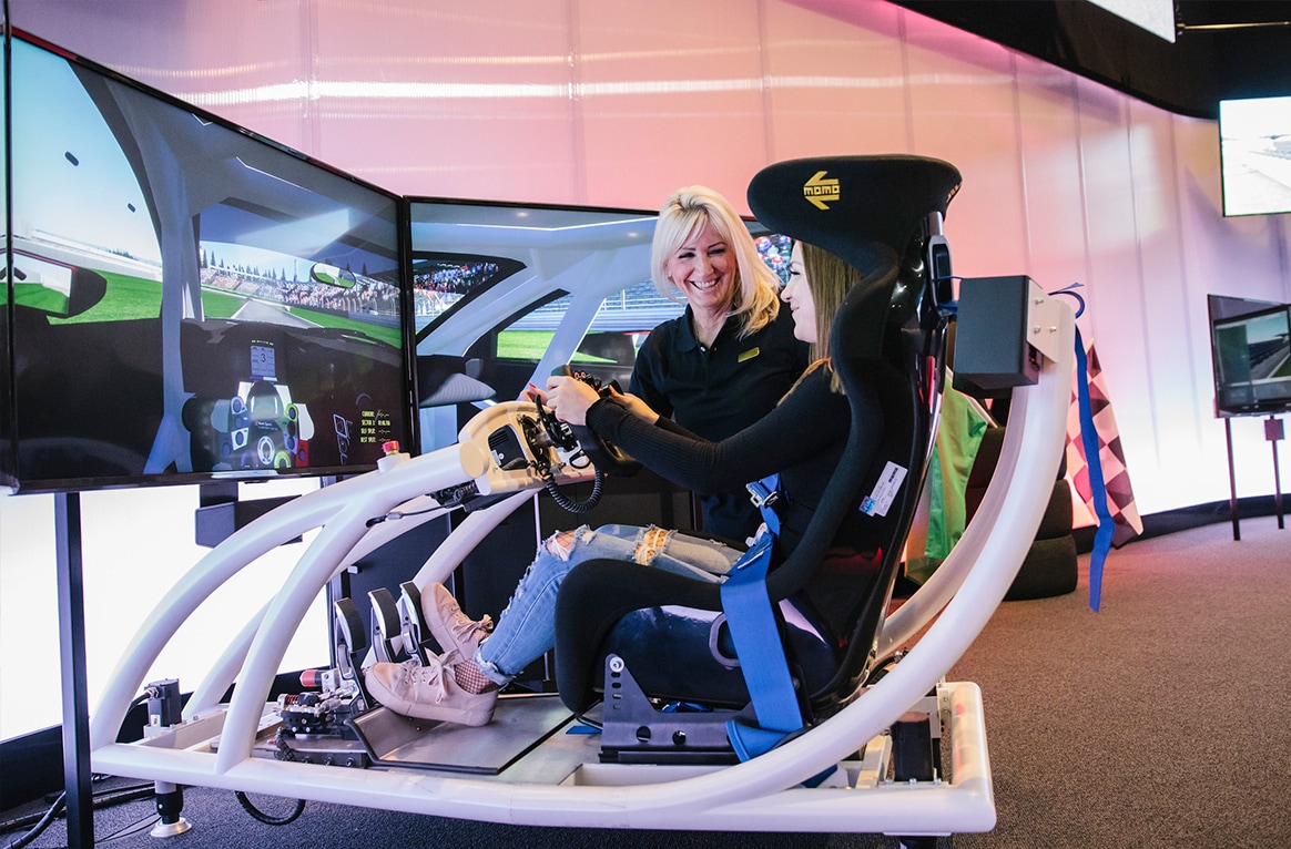 EIn Mädchen sitzt in einem Rennfahr-Simulator.
